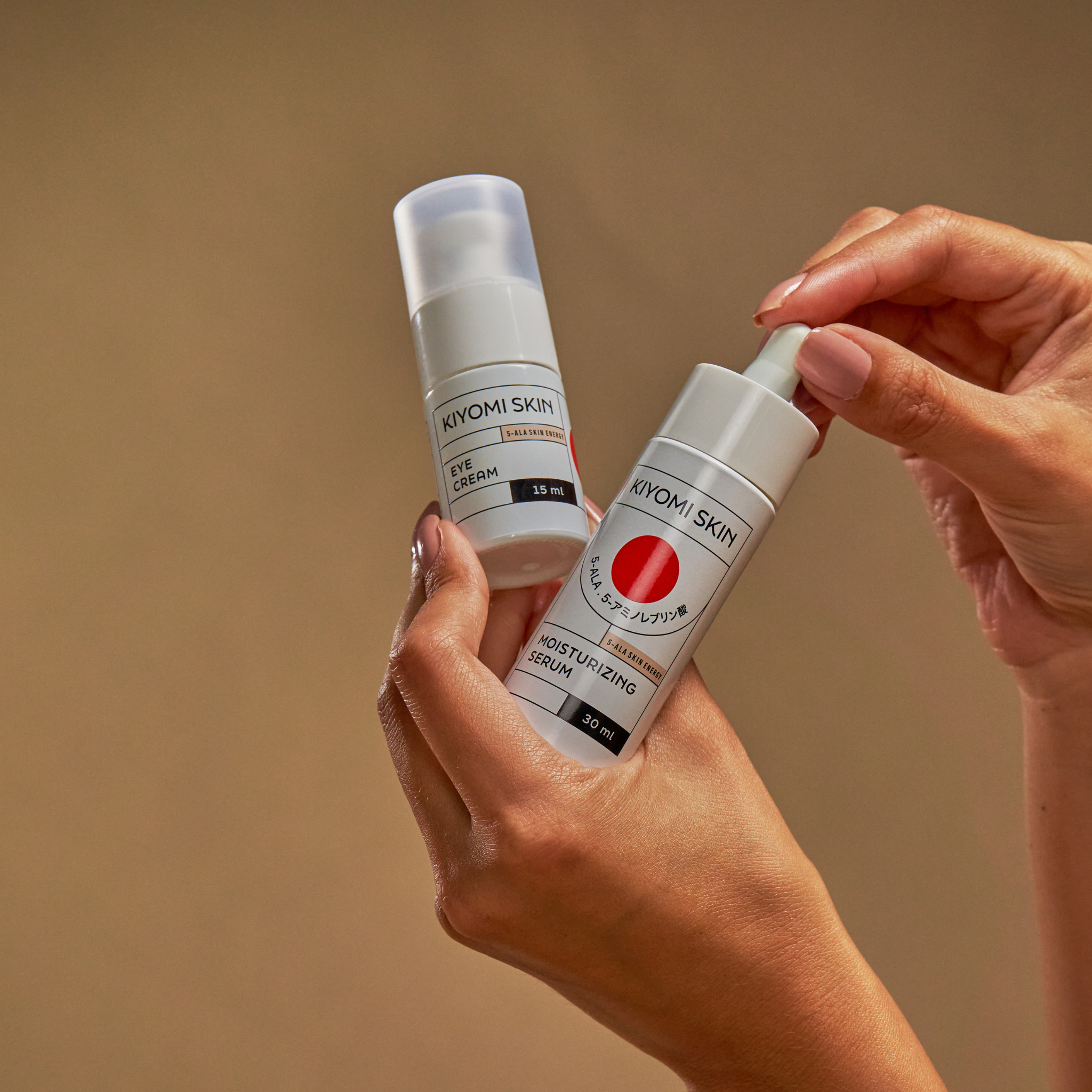 Two hands holding Early Morning Essentials against a neutral brown background.