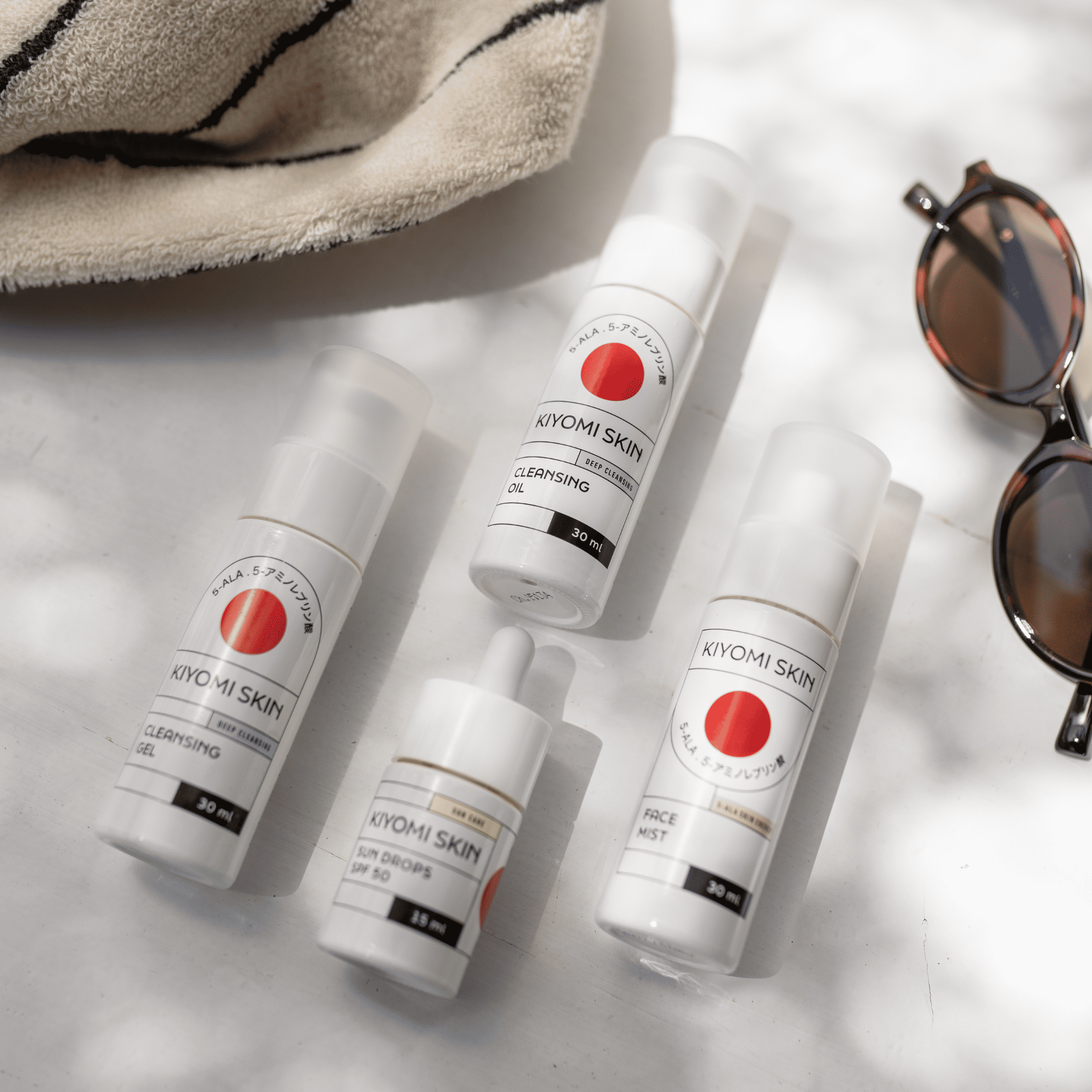 The Quick Refresh Travel Set, featuring Kiyomi Skin products like cleansing oil and SPF drops, offers UV protection and skincare on the go, displayed against a vibrant outdoor backdrop.