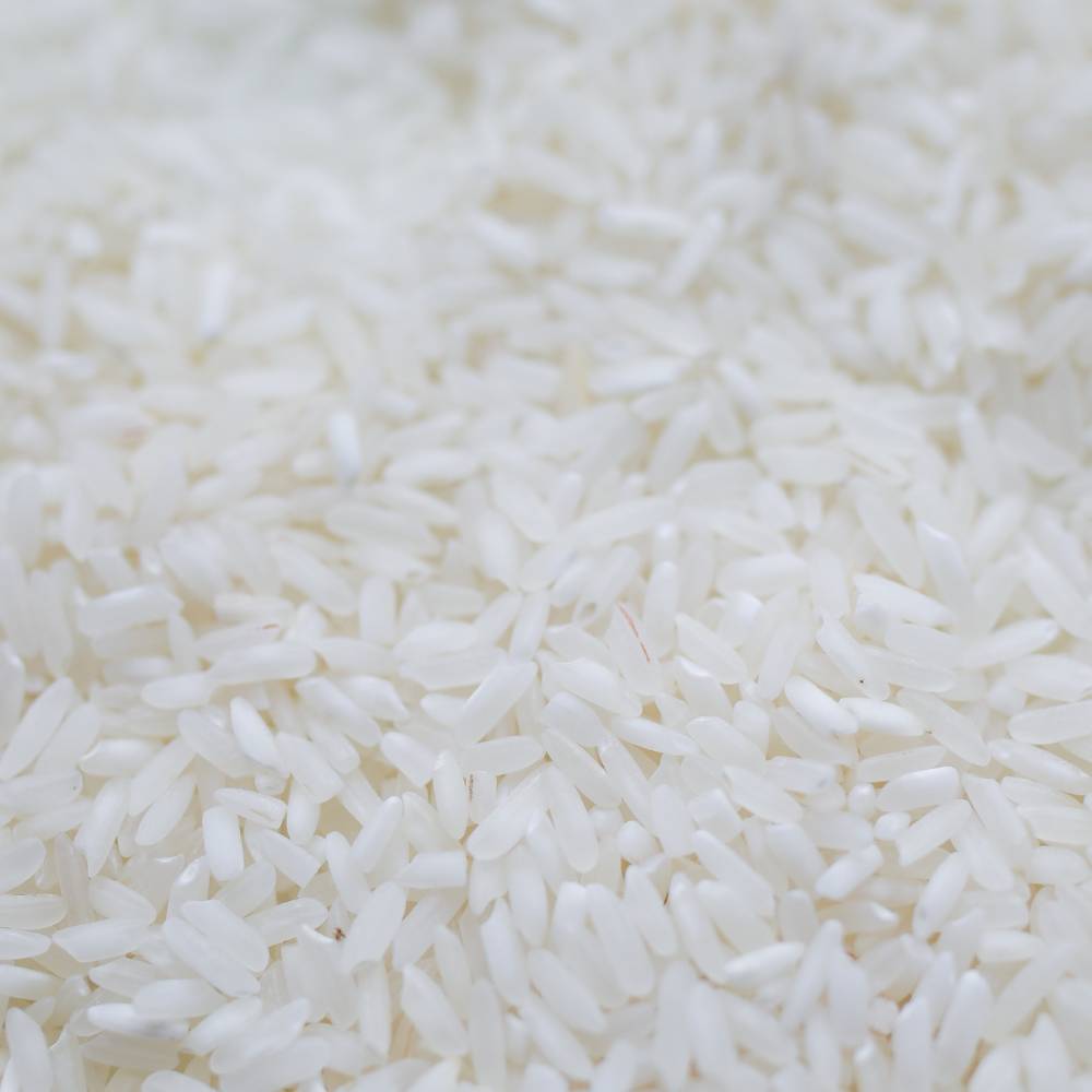 Close-up of uncooked white rice grains spread out in a pile.
