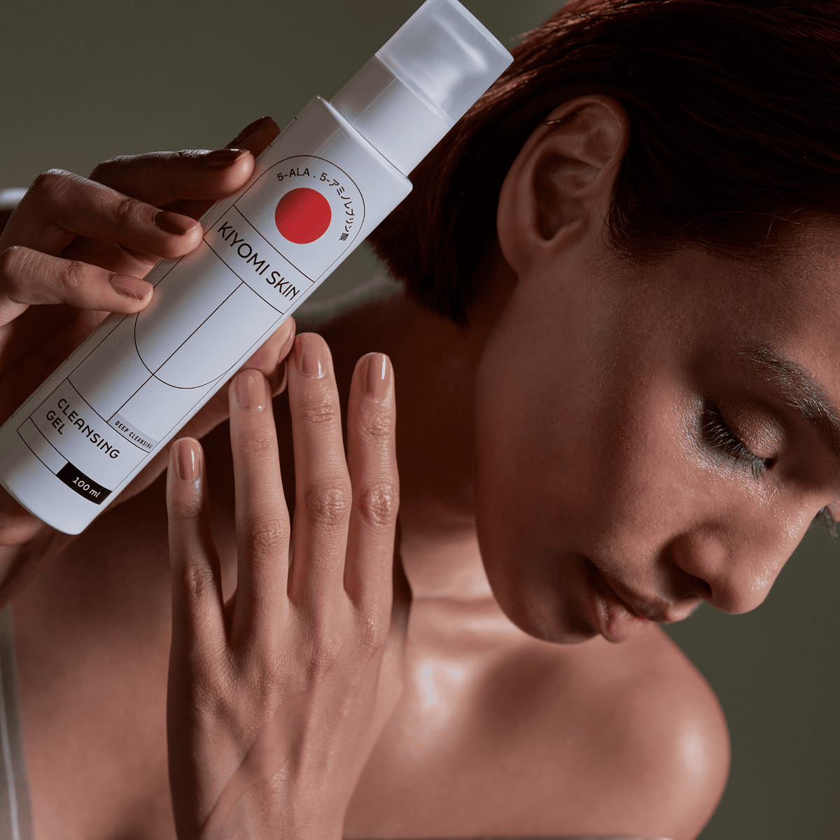 Eine Frau berührt sanft ihre Wange, während sie eine Flasche des SBI ALApromo Double Cleansing Set-Reinigungsgels nahe an ihr Gesicht hält – die ideale Wahl für eine porentiefe Reinigung.