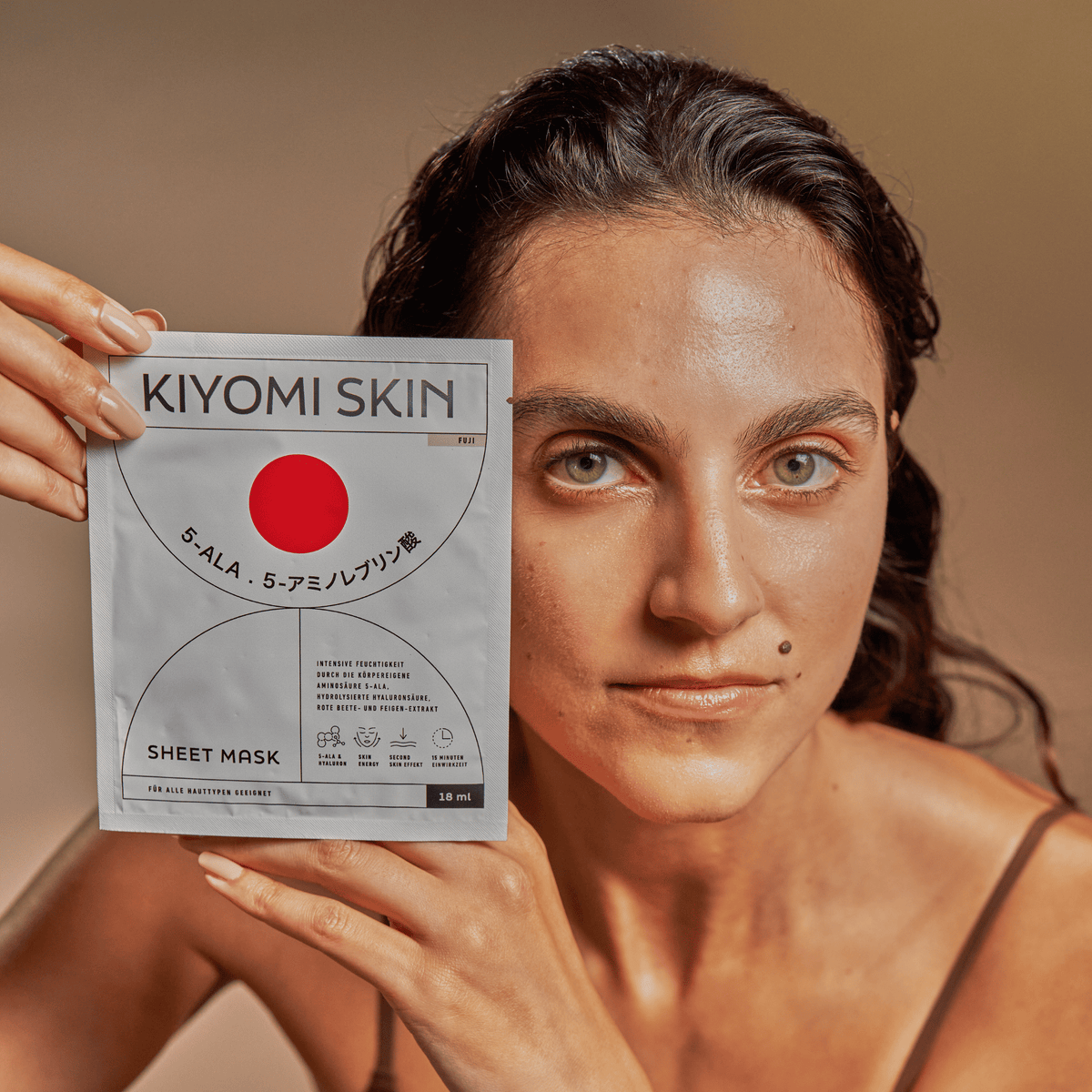 Woman holding a Sheet Mask packet, looking at the camera with a neutral expression.